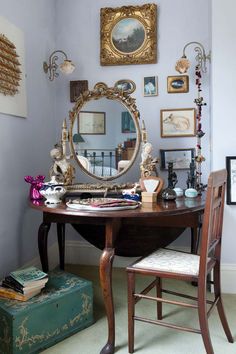 a desk with a mirror, chair and pictures on the wall