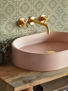 a pink sink sitting on top of a wooden counter next to a potted plant