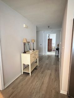 an empty hallway leading to a bedroom with a mirror on the wall and a table in front of it