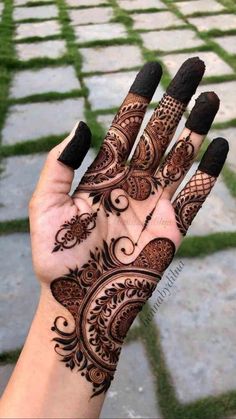 a woman's hand with henna tattoos on it, showing the intricate design