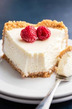 a piece of cheesecake with two raspberries on top