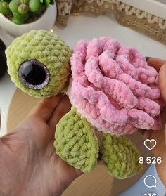 someone is holding a stuffed turtle with pink and green yarn on it's shell