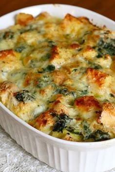 a casserole dish with cheese and spinach in it on a white cloth