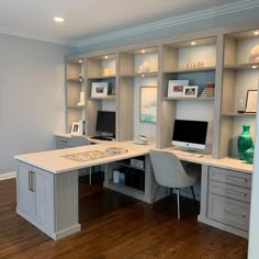 a home office with built in desks and cabinets