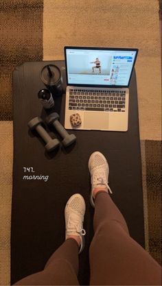 a laptop computer sitting on top of a wooden table next to a person's legs