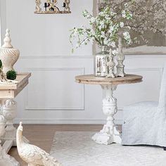 a living room filled with white furniture and flowers in vases on top of tables