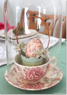 a teacup with an egg in it under a glass dome