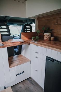 the interior of a camper with wood counter tops and white cabinets, including a dishwasher