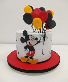 a mickey mouse cake with balloons on top