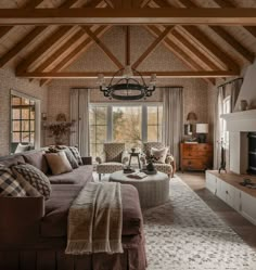 a living room filled with furniture and a fire place under a wooden beamed ceiling