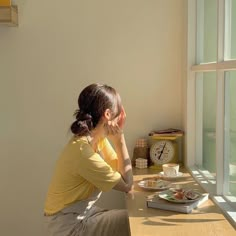 a woman sitting at a table looking out the window