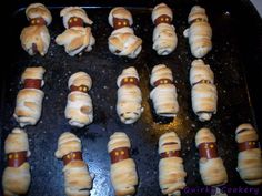 pigs in a blanket on a baking sheet ready to go into the oven with hot dog buns