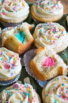 cupcakes with white frosting and sprinkles on a green tray