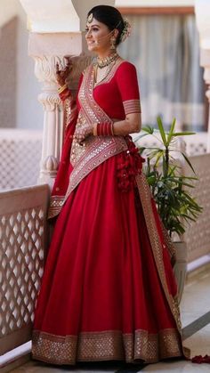 a woman in a red and gold bridal gown standing next to a white pillar