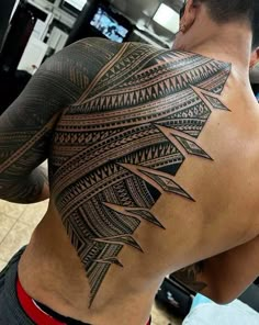 a man's back with an intricate tattoo design on it