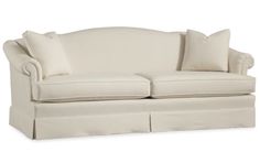 a white couch with two pillows on the back and one pillow in the middle, sitting next to each other