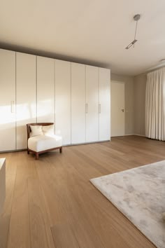 an empty room with wooden floors and white cupboards on either side of the wall