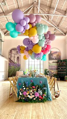 a table with flowers and balloons hanging from the ceiling