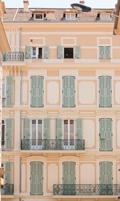 an apartment building with green shutters and balconies