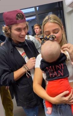 a man holding a baby in his arms while another woman holds him close to her face