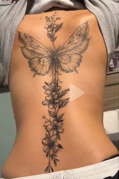 the back of a woman's stomach with flowers and a butterfly tattoo on it