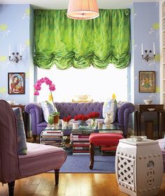 a living room filled with purple furniture and green drapes on the windowsills