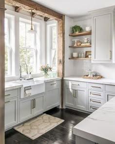 a kitchen with lots of white cabinets and wooden shelves on the wall, along with an area rug