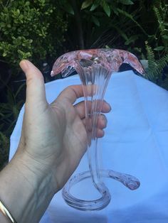 a hand holding a clear glass vase on top of a blue cloth covered tablecloth