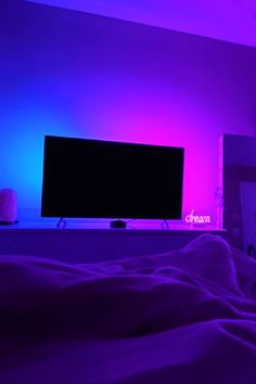 a flat screen tv sitting on top of a wooden stand next to a purple wall