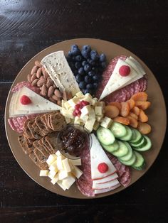 an assortment of cheeses, crackers, and fruits on a plate with nuts