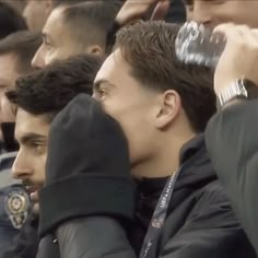 a group of men sitting next to each other in front of a man holding a water bottle