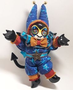 a blue and orange cat figurine with stars on it's body, wearing a costume