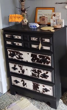 a black dresser with brown and white cow print drawers