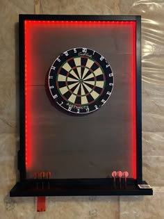 a dart board with darts in the center and red lights around it on a black shelf