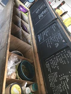 an open chalkboard menu on the side of a wooden box filled with containers and bowls