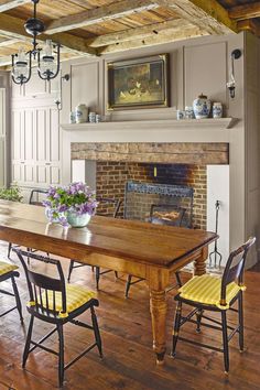 a dining room table with yellow chairs and a fire place in the corner behind it