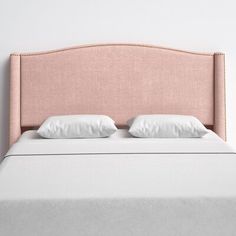 a pink headboard with two white pillows on top of it, against a white wall