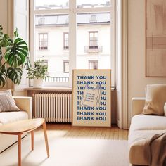 a living room filled with furniture and a large window covered in thank you sign next to a plant