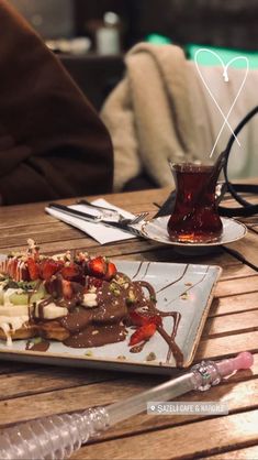 a plate with food on it sitting on a wooden table next to a glass cup