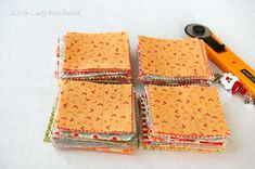 several pieces of cloth are stacked on top of each other with an orange scissor next to them