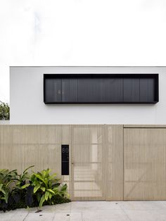 an entrance to a building with wooden doors and plants in the foreground, on a cloudy day