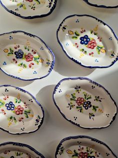 several plates with flowers painted on them are lined up