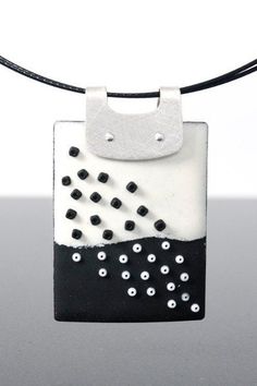 a black and white square pendant on a leather cord with silver beads hanging from it