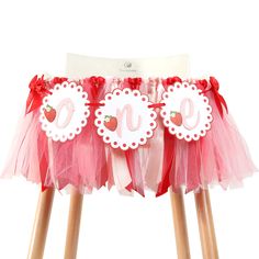 two wooden stools with pink and red tulle skirts on them, one has a monogrammed number