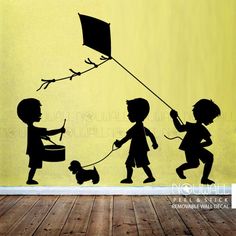 three children playing with a kite on a yellow wall in an empty room that says vali decal depot