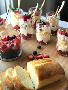 several desserts are arranged on a table with strawberries and blueberries in jars