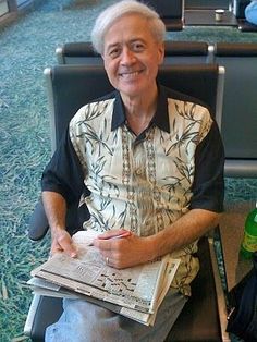 an older man sitting in a chair holding a newspaper