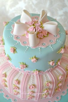 a blue cake with pink flowers and bows on top