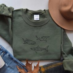 🦈 A hammerhead, a great white, and a whale shark walk into a bar... 🌊 The greatest gift for the shark lover in your life. Maybe that's you. The embroidery will delight you as this crewneck sweatshirt keeps you warm and fuzzy.  Available in plus sizes (see size chart in photo lineup). 🌞 FEATURES: * 50% cotton, 50% polyester (PRE-SHRUNK) * Medium-heavy fabric (8.0 oz/yd² (271.25 g/m * Classic fit * Runs true to size ➡️ Size up 1 to 2 sizes for that OVERSIZED vibe. 😎 * 1x1 athletic rib knit col Shark Clothing Aesthetic, Shark Sweater, Graphic Tee With Shark Design And Crew Neck, Shark Sweatshirt, Casual Summer T-shirt With Shark Design, Cheap Crew Neck T-shirt With Shark Design, Casual Cotton T-shirt With Shark Design, Shark Gifts, Shark Lover