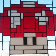 a close up of a red and white stained glass window with a brick face on it